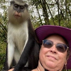 a woman in a purple hat is holding a monkey on her shoulder .