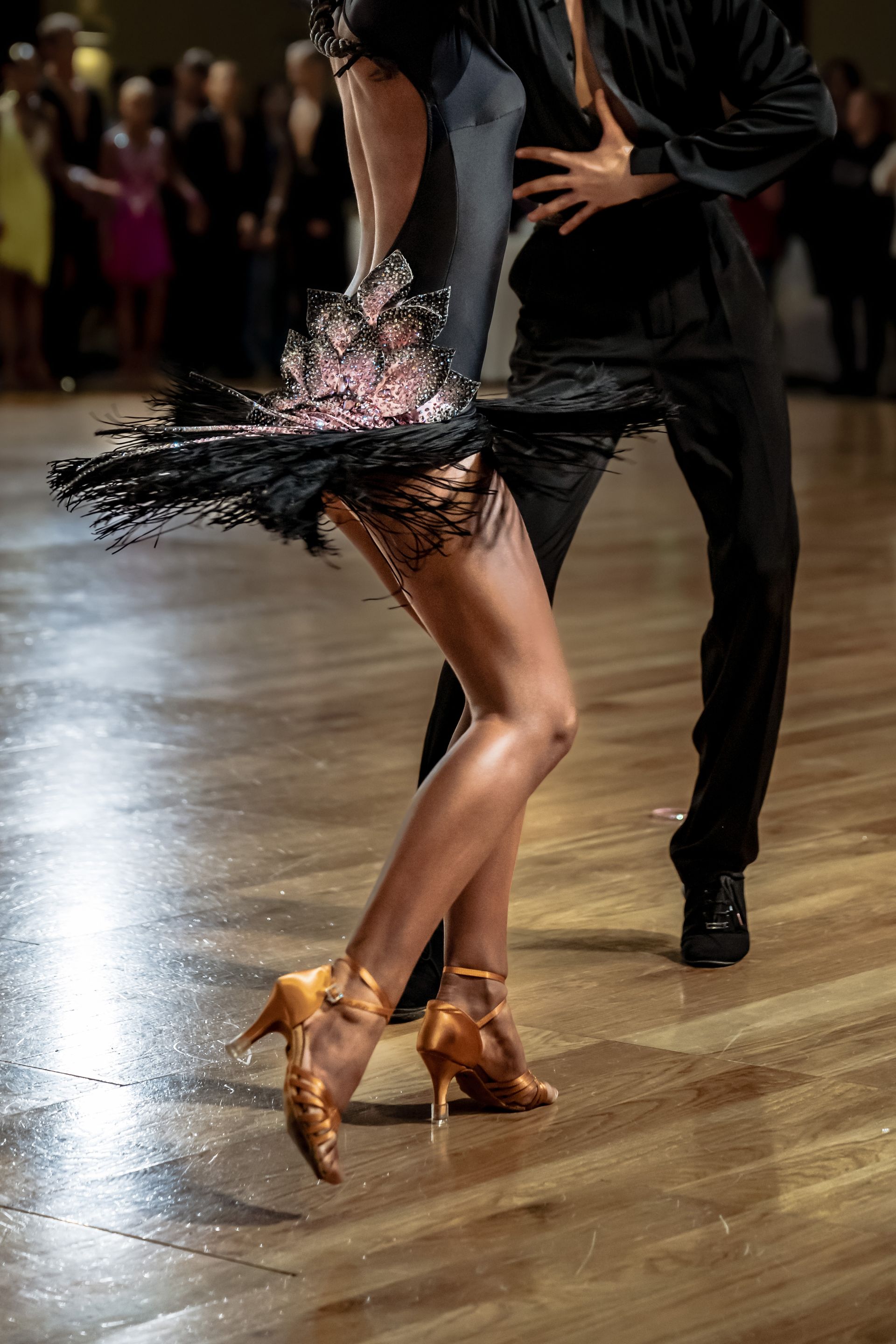 A man and a woman are dancing salsa on a wooden floor.