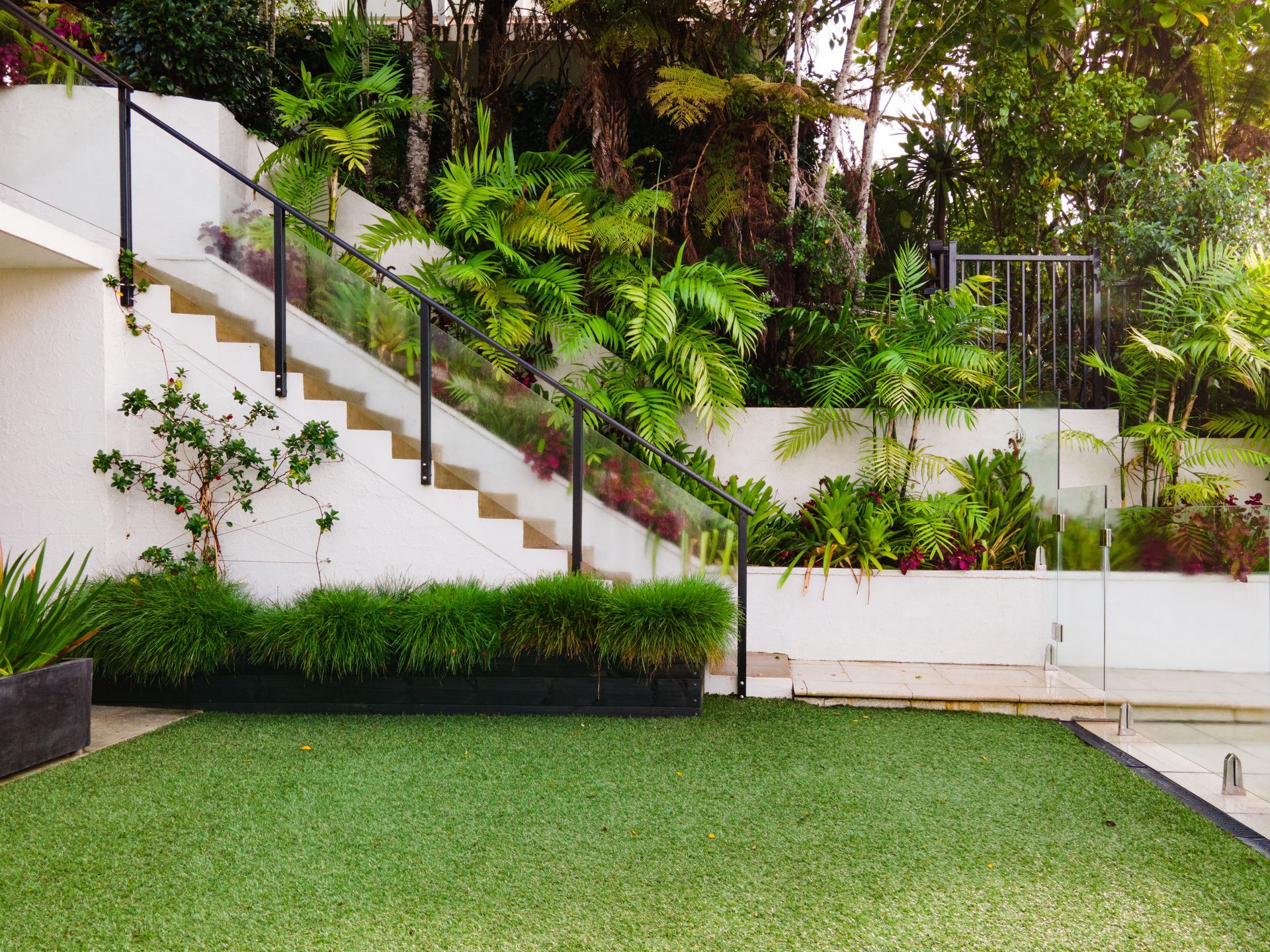 White House with a lush green lawn and staircase adorned with vibrant plants.