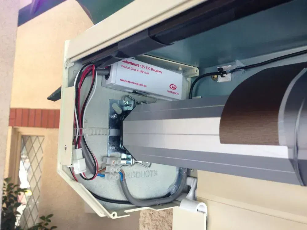 A motorized awning mechanism with electrical components; beige and brown.