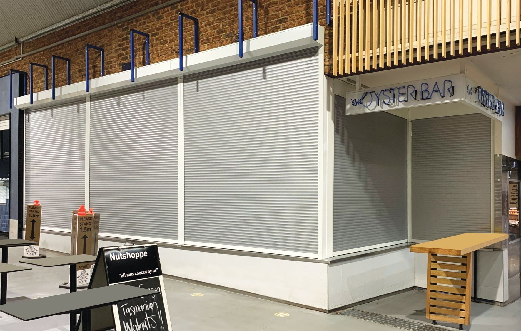 Corner building with rippled gray and white facade, kitchen/bar sign, and small wooden table.
