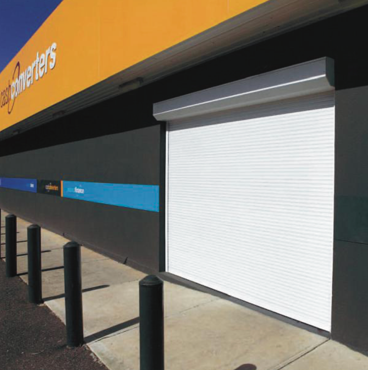 White roller shutter on a commercial building exterior, with blue, orange, and black accents.