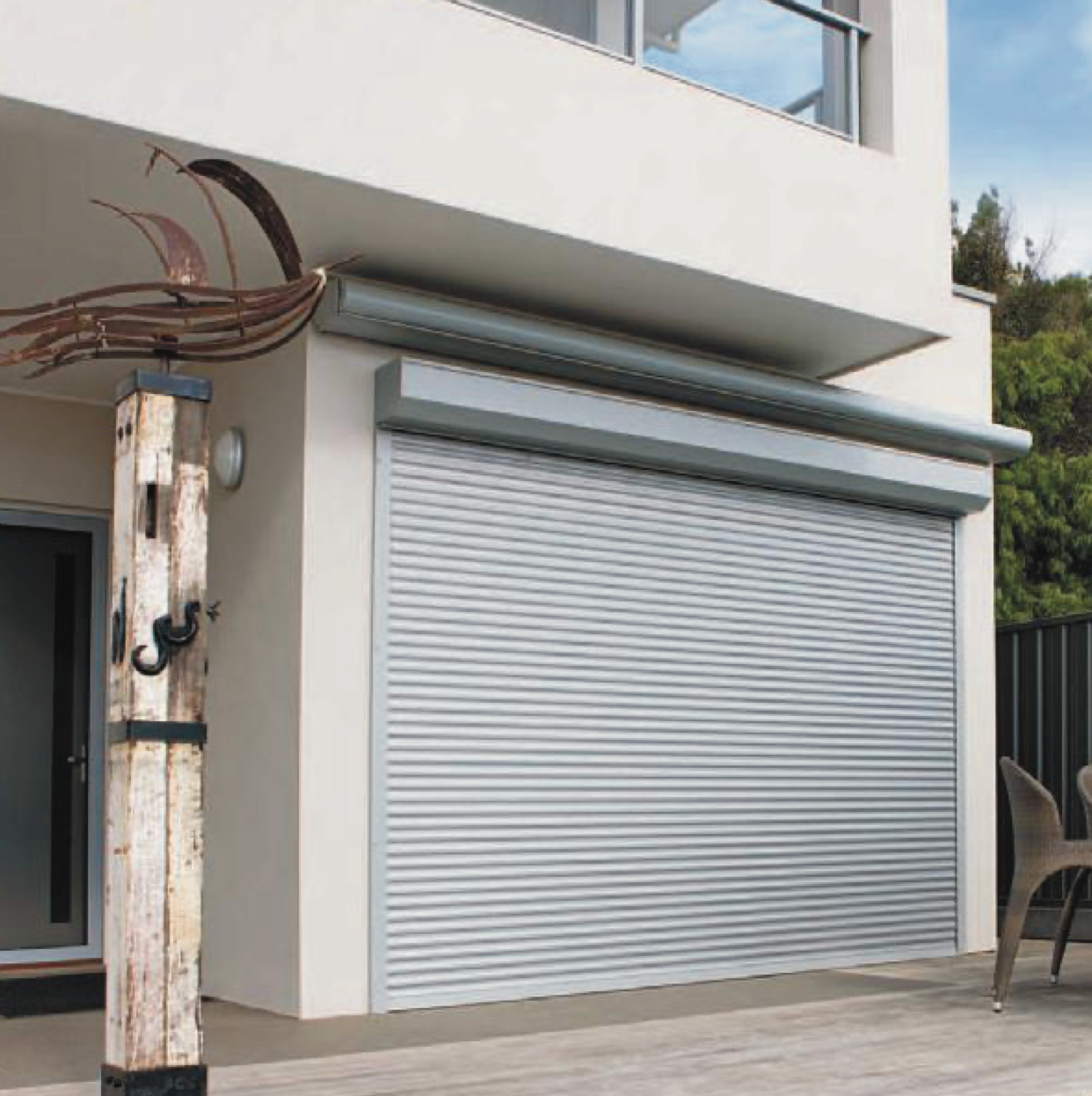 Gray rolling shutter on a white building exterior, possibly for a garage or patio.