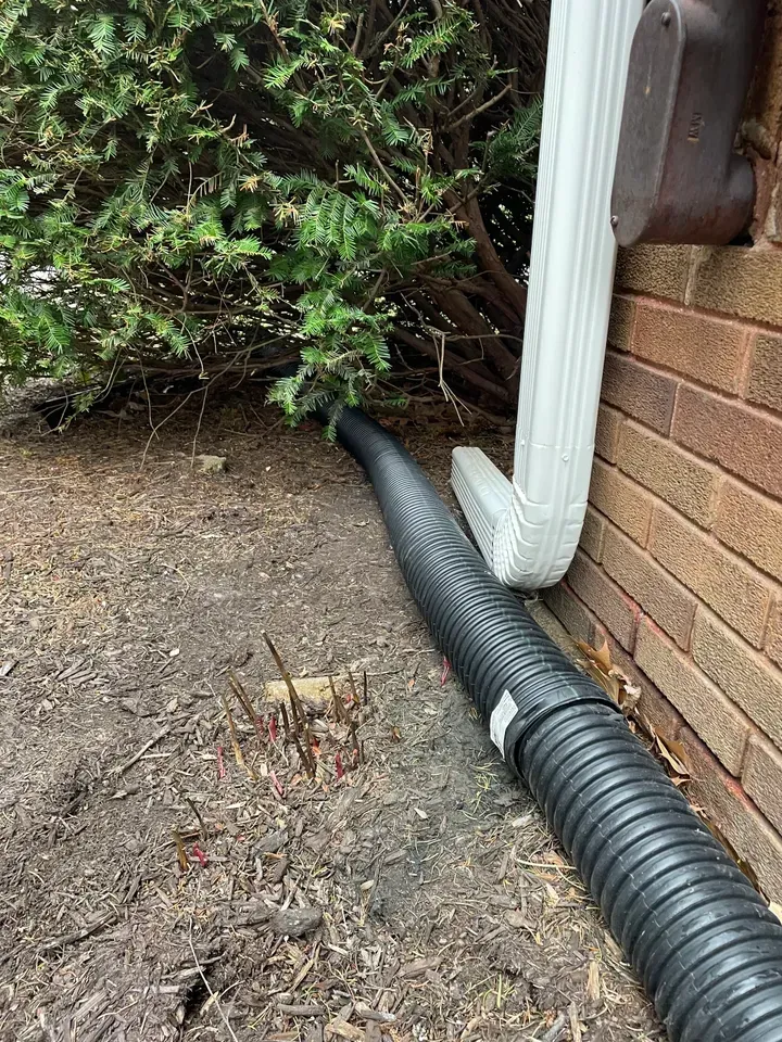 Gutter extension with drainage pipe for water diversion. Expert gutter installation service and siding and gutter repair