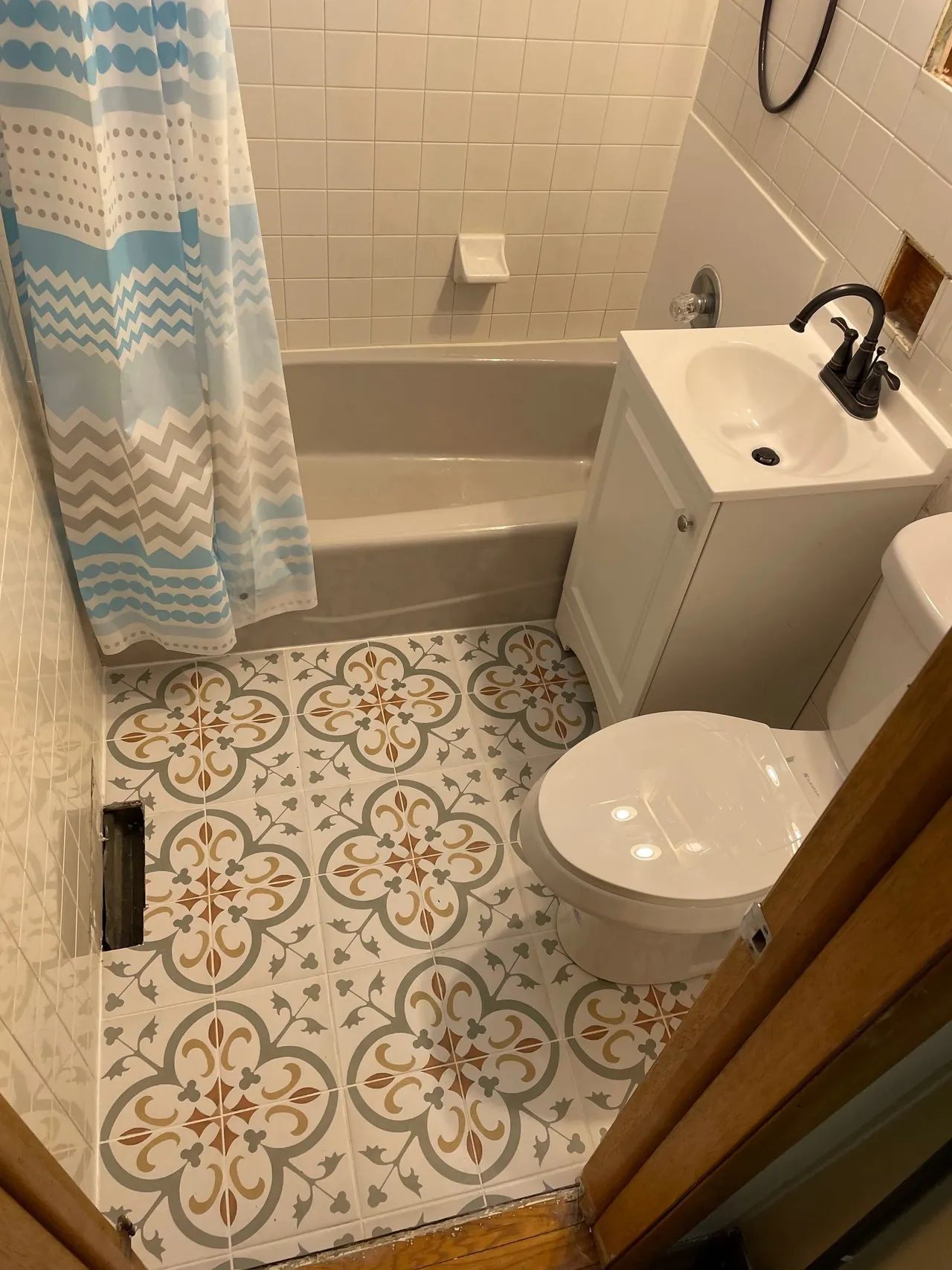 Bathroom remodel with new tile flooring and updated fixtures. Professional home remodeling services and bathroom caulking service.