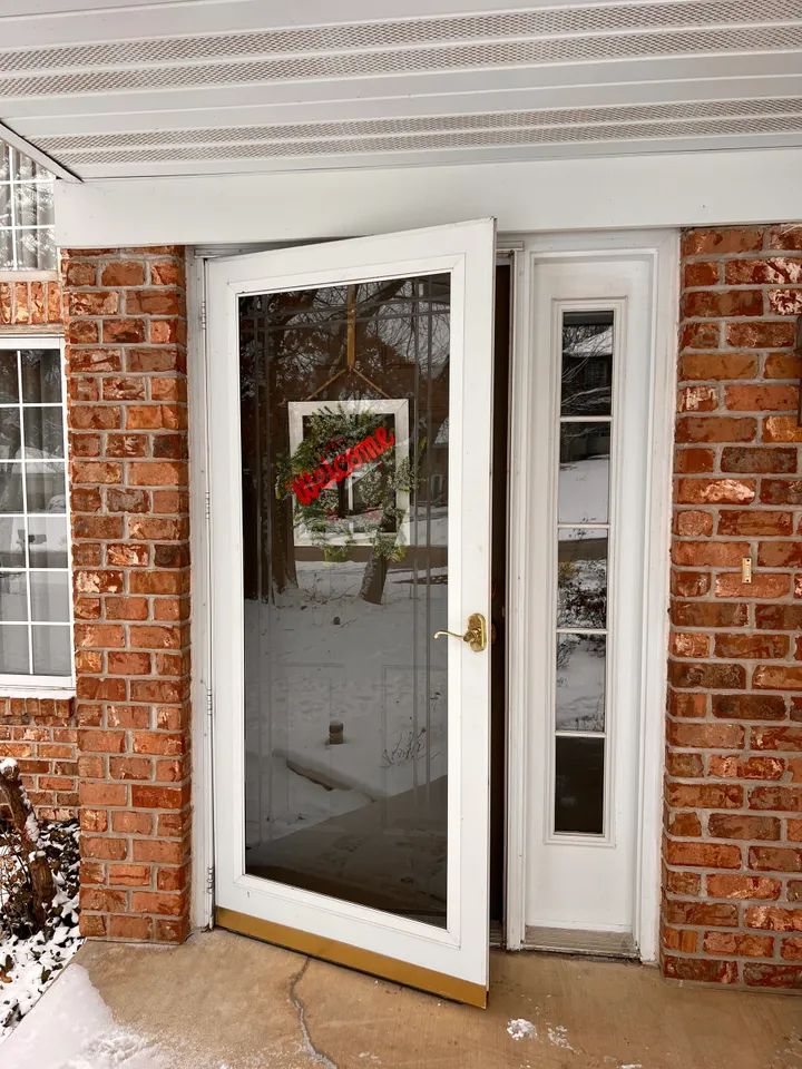 Storm door installed on brick home entrance. Expert door installation and handyman door repair for security and insulation.