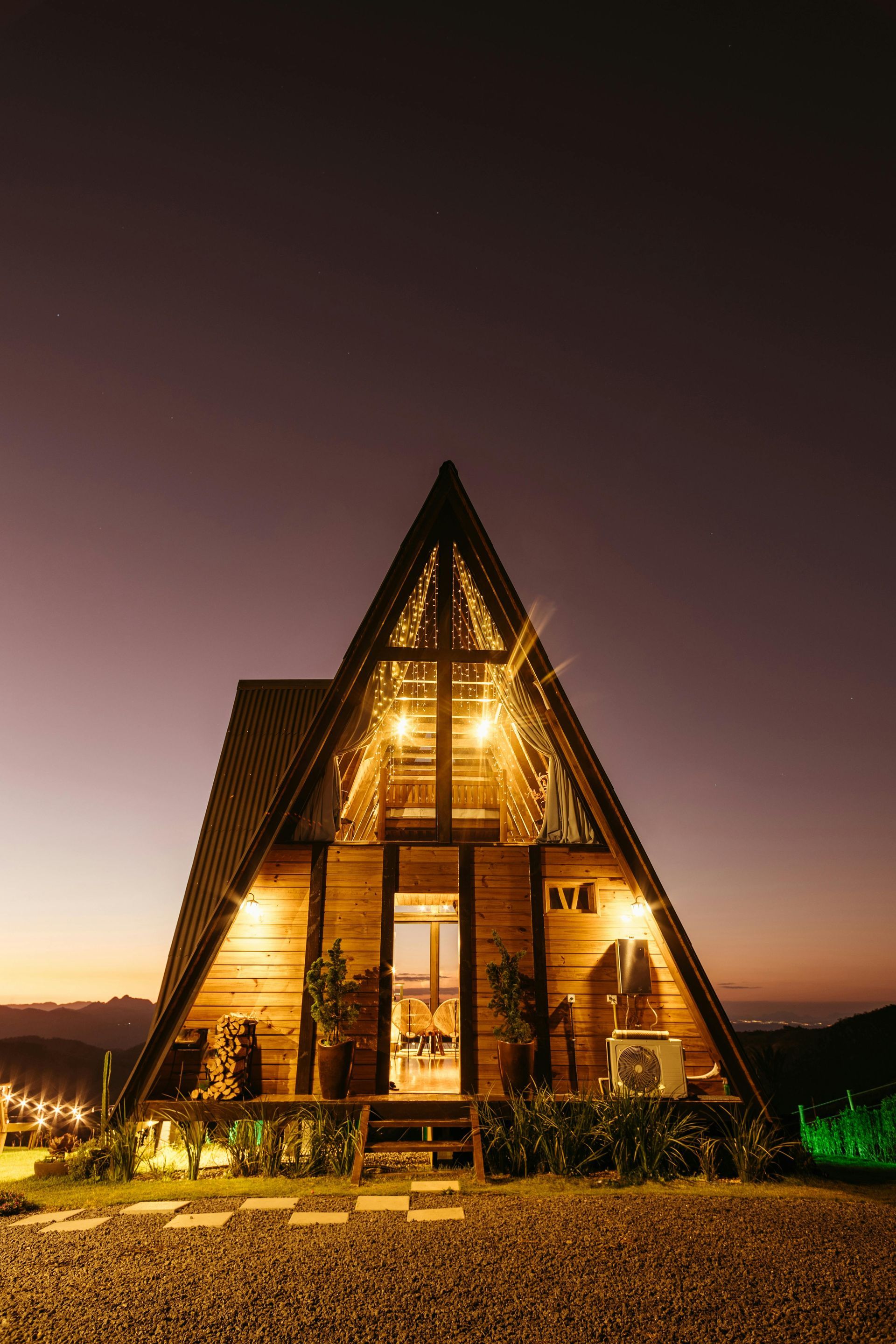 A small wooden a frame house is lit up at night.