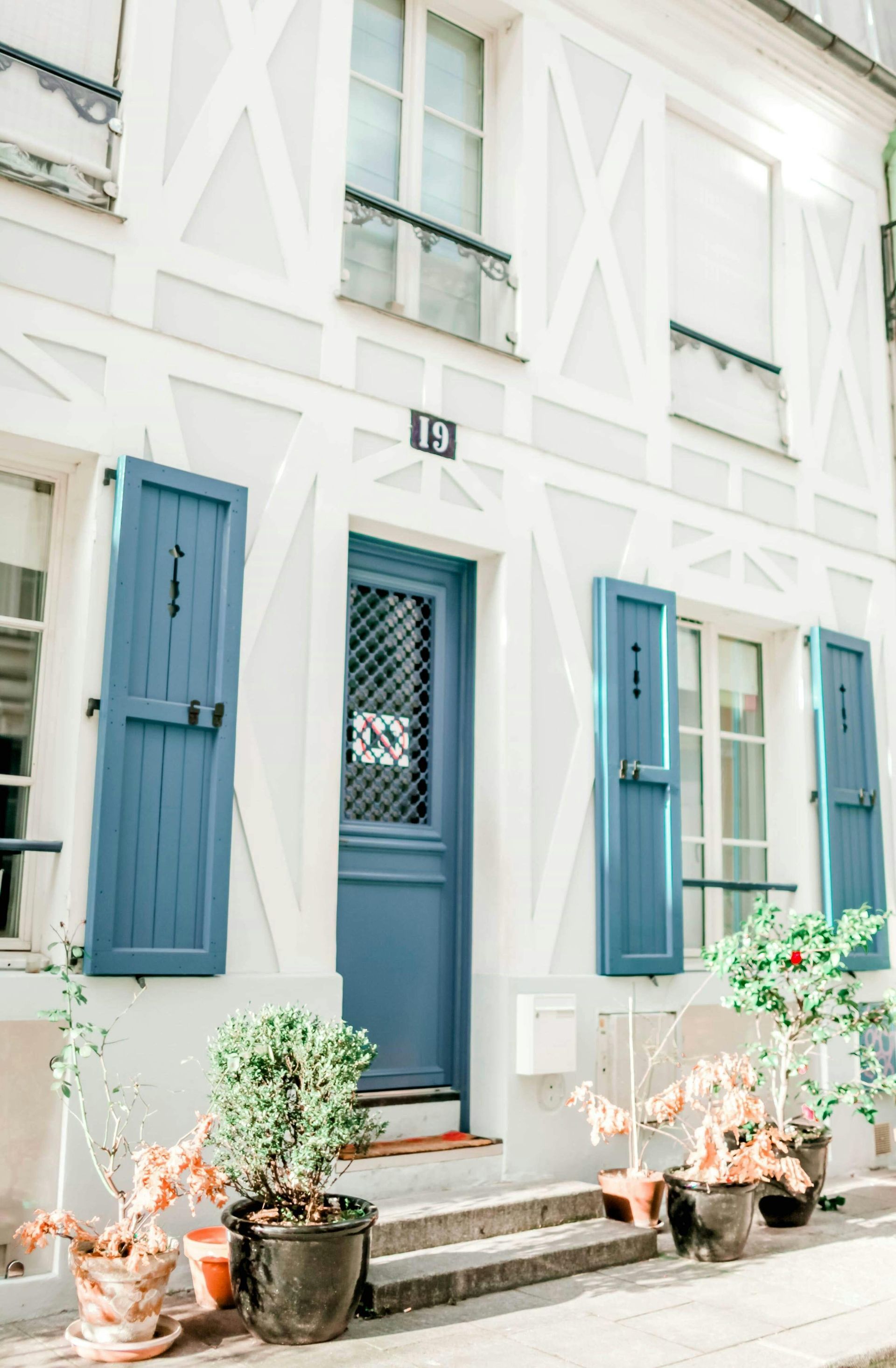 A white house with blue shutters and a blue door.