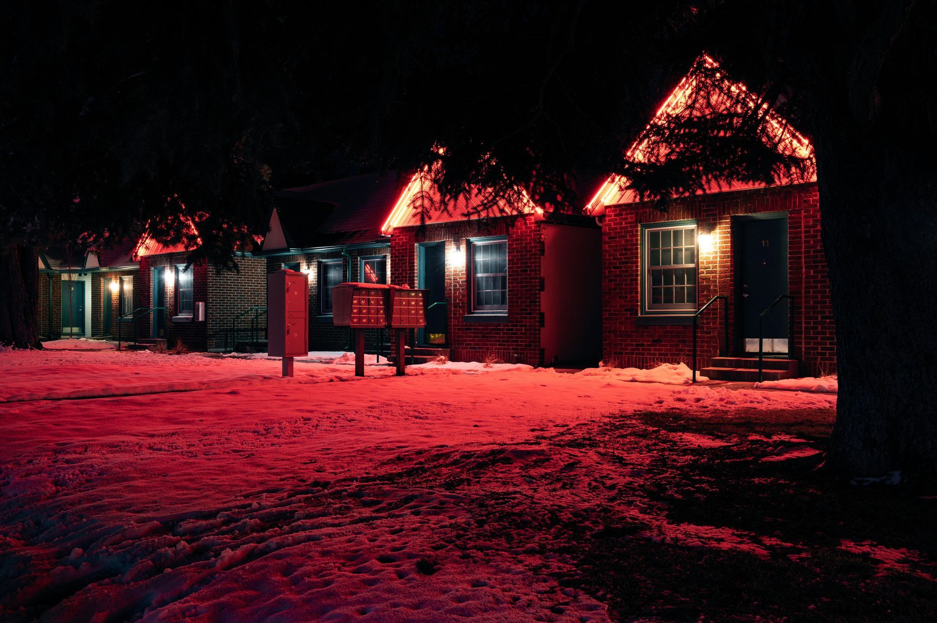 A row of houses are lit up with red lights at night