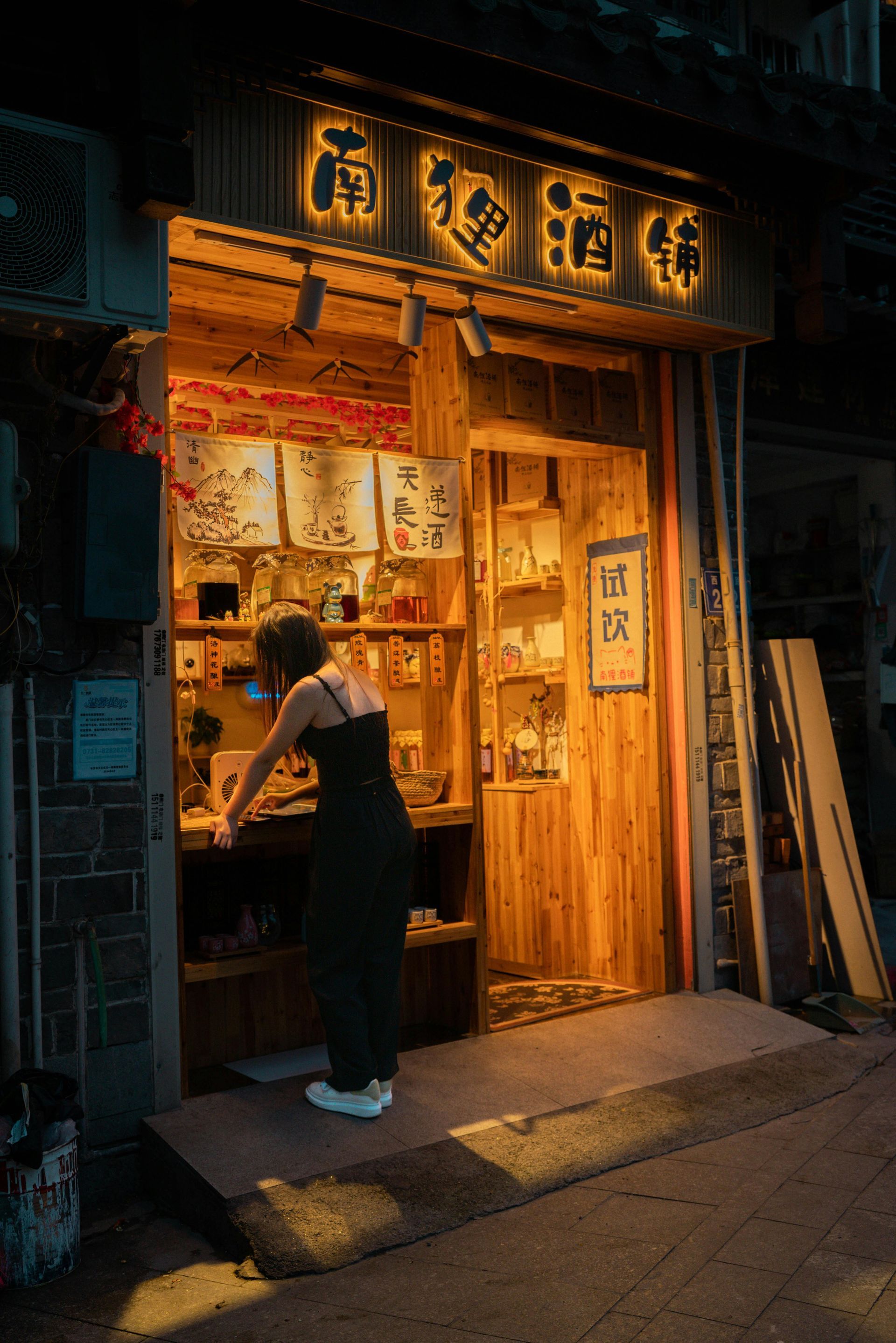 A woman is standing in front of a restaurant at night.