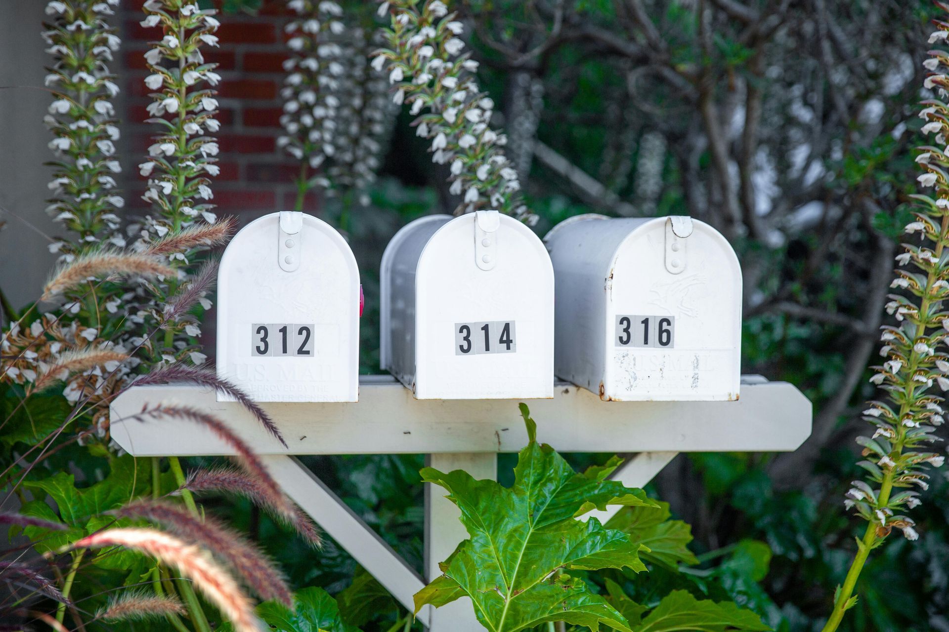 Three white mailboxes are sitting on top of a wooden post.