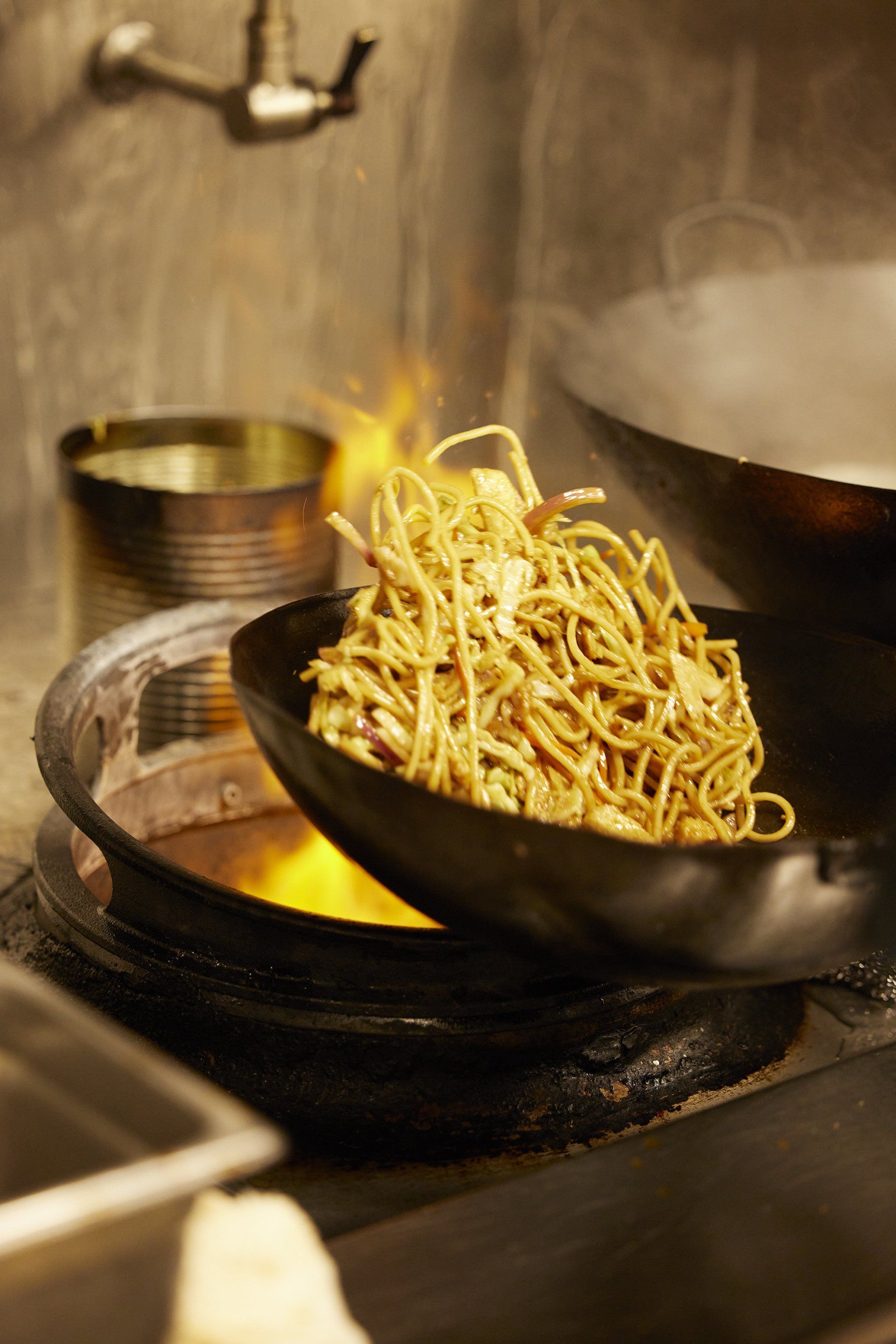wok over open flame with noodles