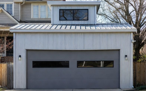 Gray garage with metal siding and a gray garage door. Above is a window.