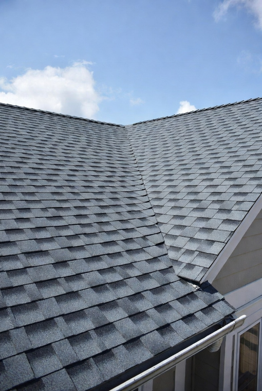 Gray shingle roof against a blue sky with some clouds; a white gutter is visible.