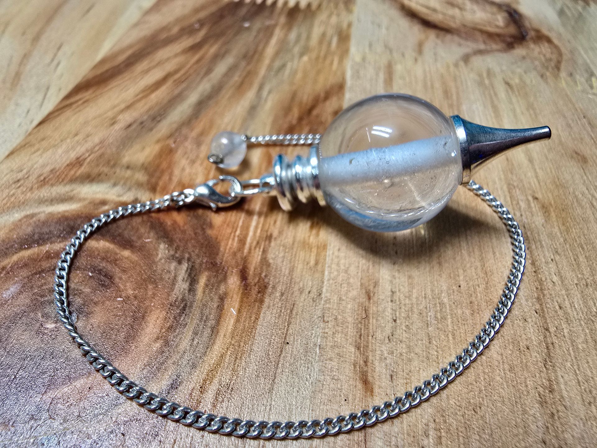 Een slinger aan een ketting staat op een houten tafel