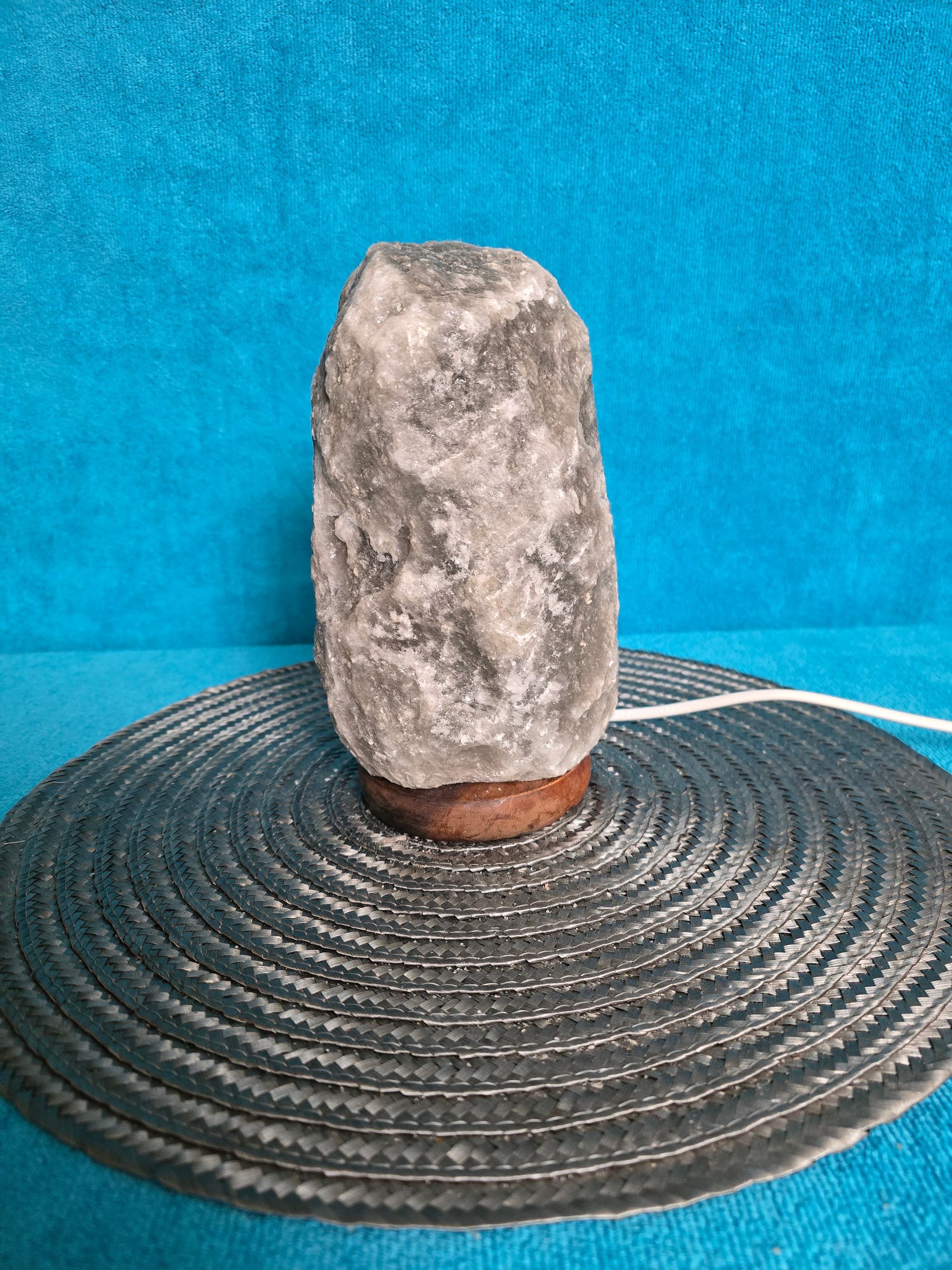 Een zoutlamp staat op een zwarte mat op een tafel.