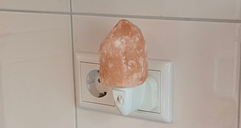 Een oranje, oplichtend nachtlampje van Himalayazout, aangesloten op een stopcontact.