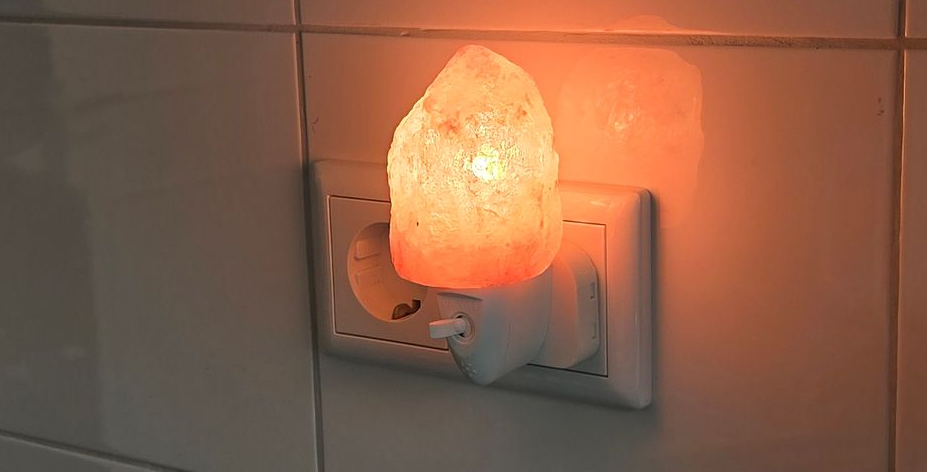 Een oranje, oplichtend nachtlampje van Himalayazout, aangesloten op een stopcontact.