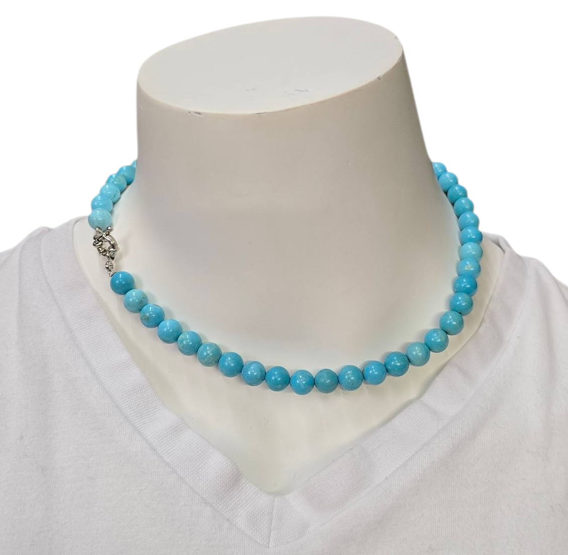 Een ketting van turkooizen kralen om de nek van een paspop, de sluiting is zichtbaar.