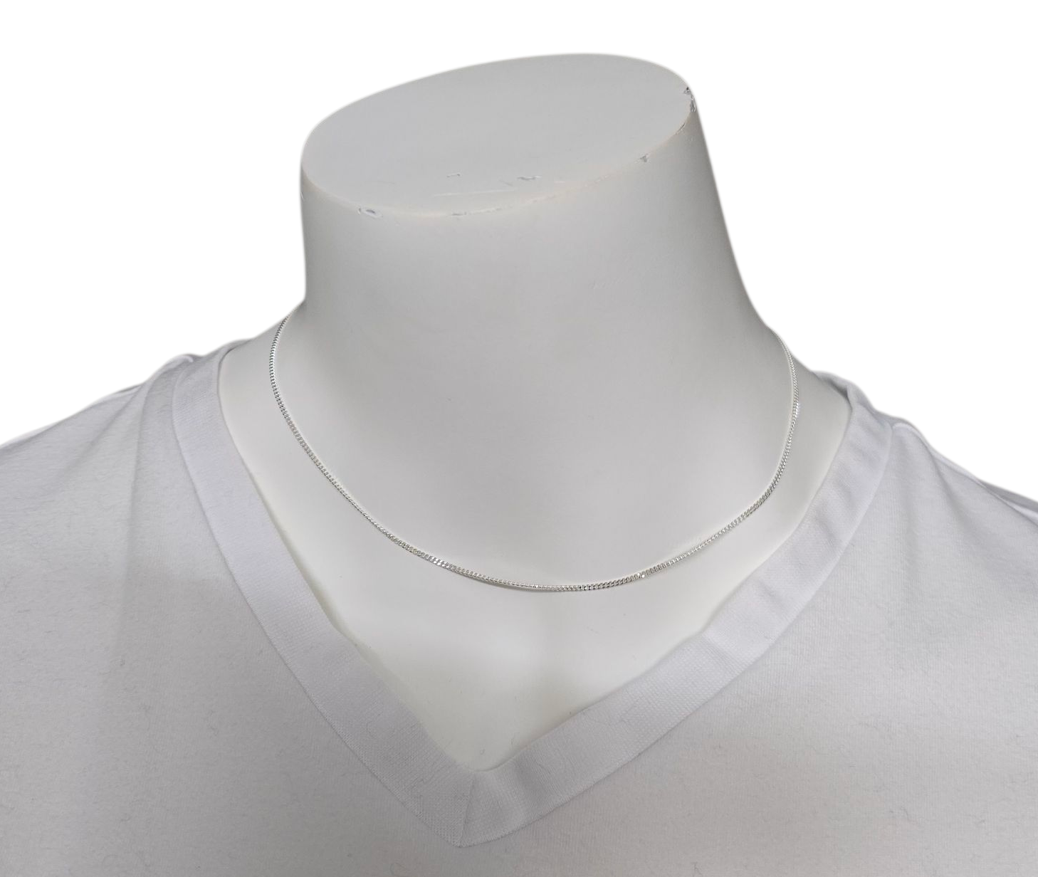 Zilveren ketting om de nek van een witte paspop die een wit shirt met V-hals draagt.