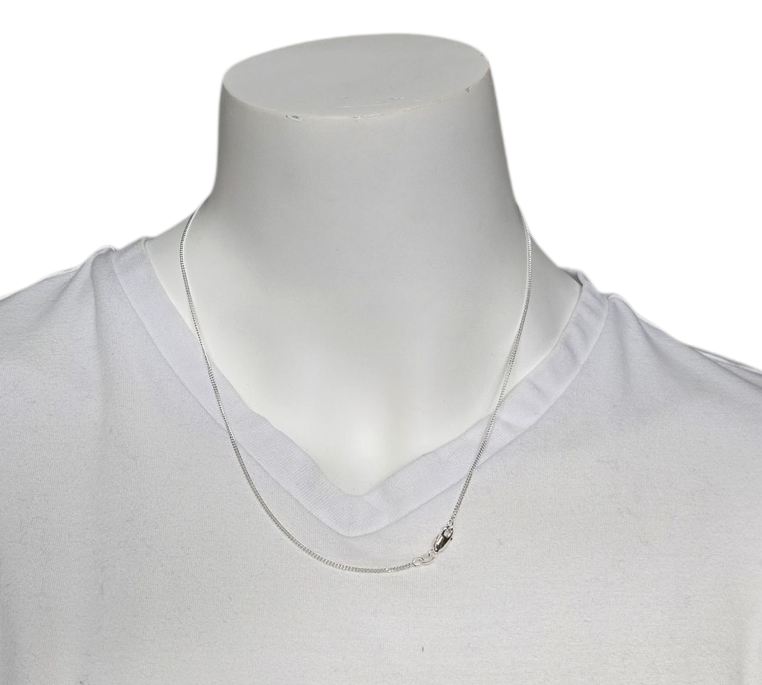 Zilveren ketting om de nek van een witte paspop die een wit shirt met V-hals draagt.