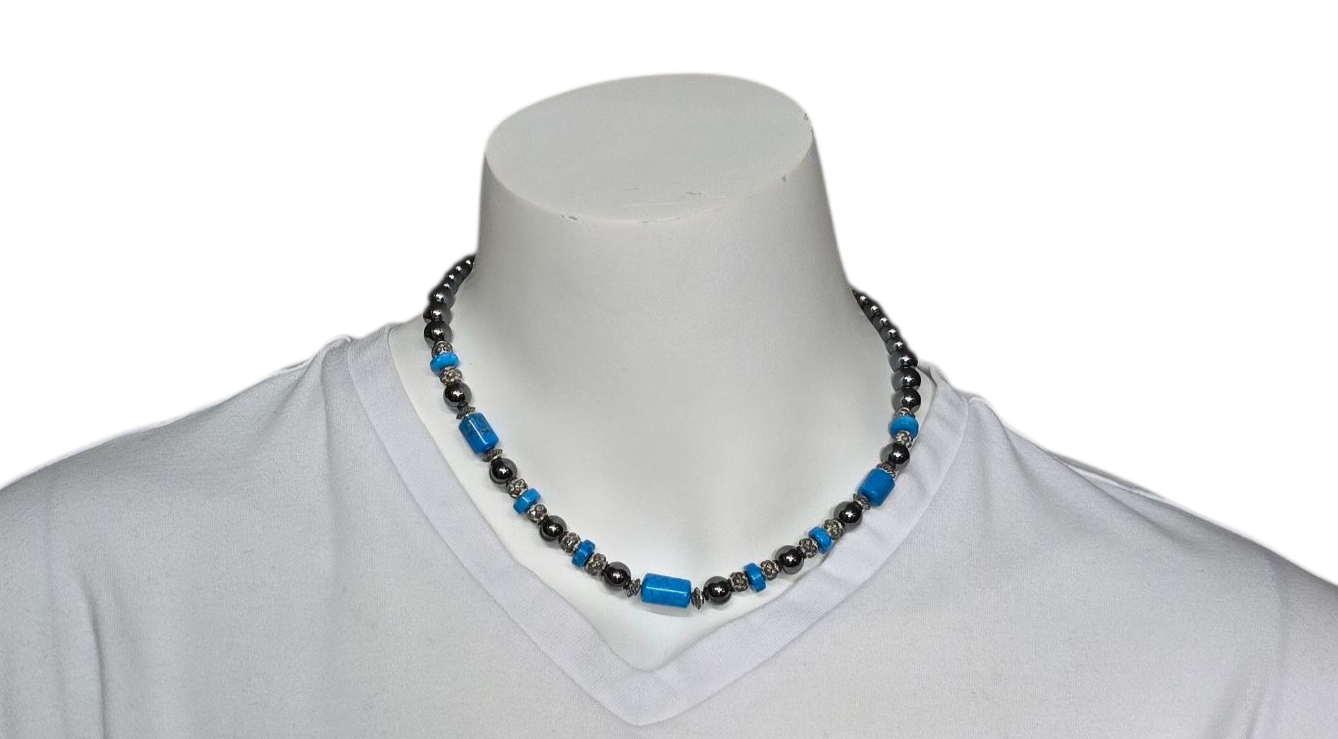 Een blauwe en grijze kralenketting op een wit T-shirt en de nek van een paspop.