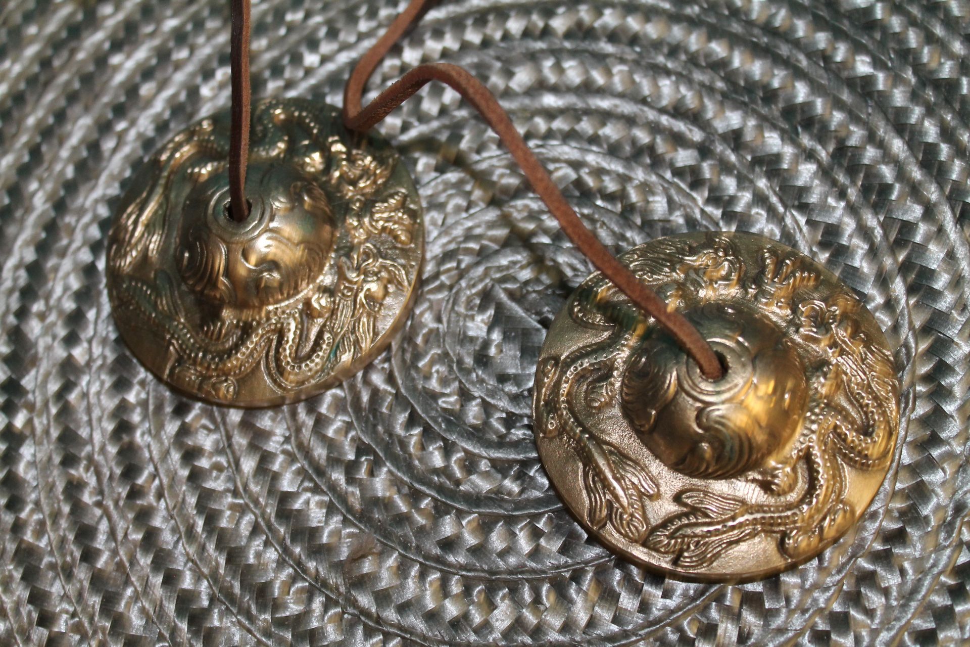 Een paar koperen cimbalen liggen op een metalen oppervlak.