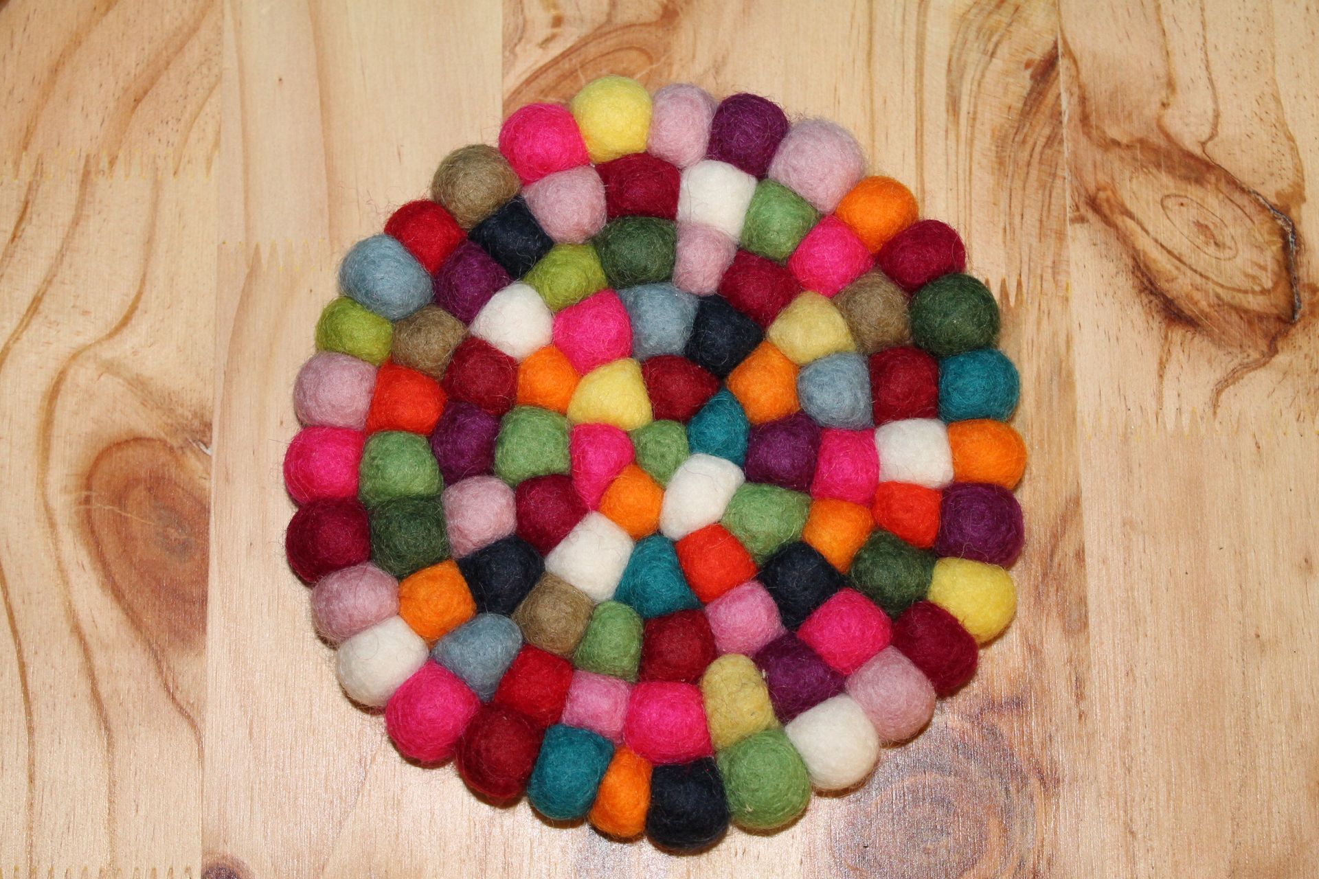 Een ronde onderzetter gemaakt van kleurrijke ballen op een houten tafel