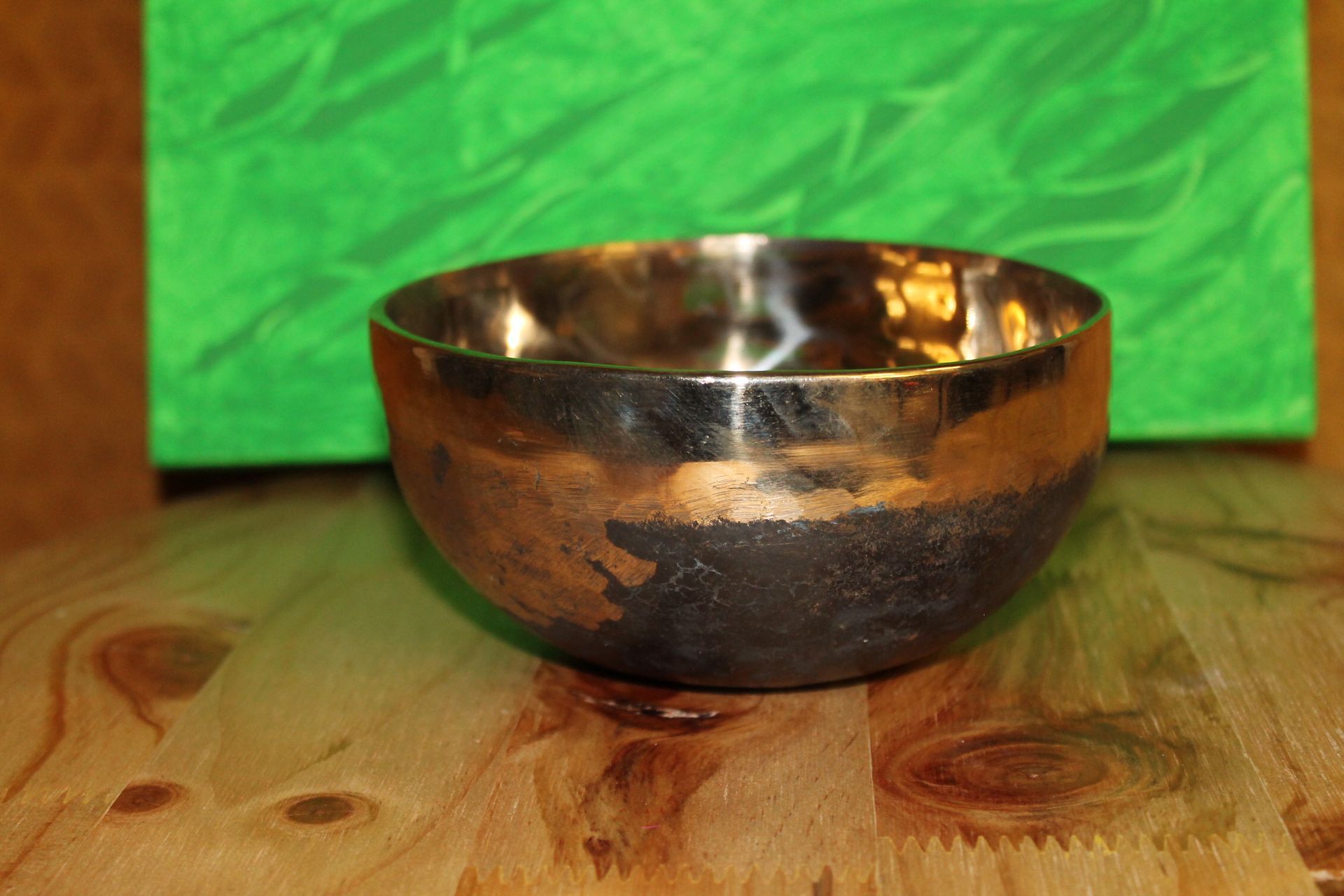 Een kleine metalen kom staat op een houten tafel.