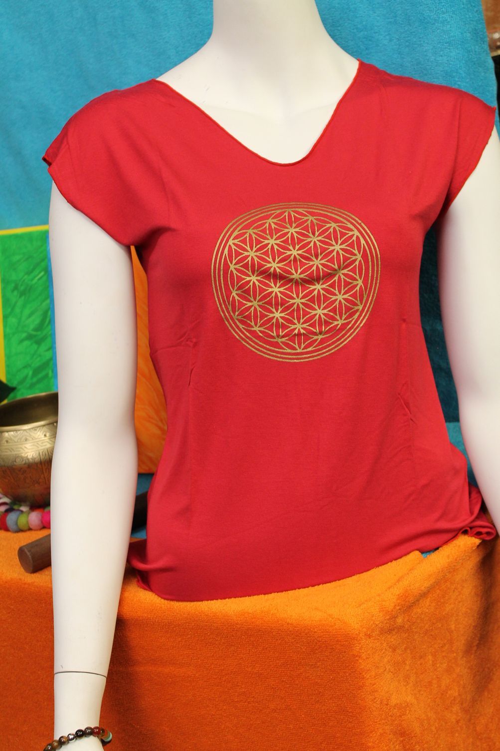 Een mannequin draagt ​​een rood shirt met een bloem des levens erop