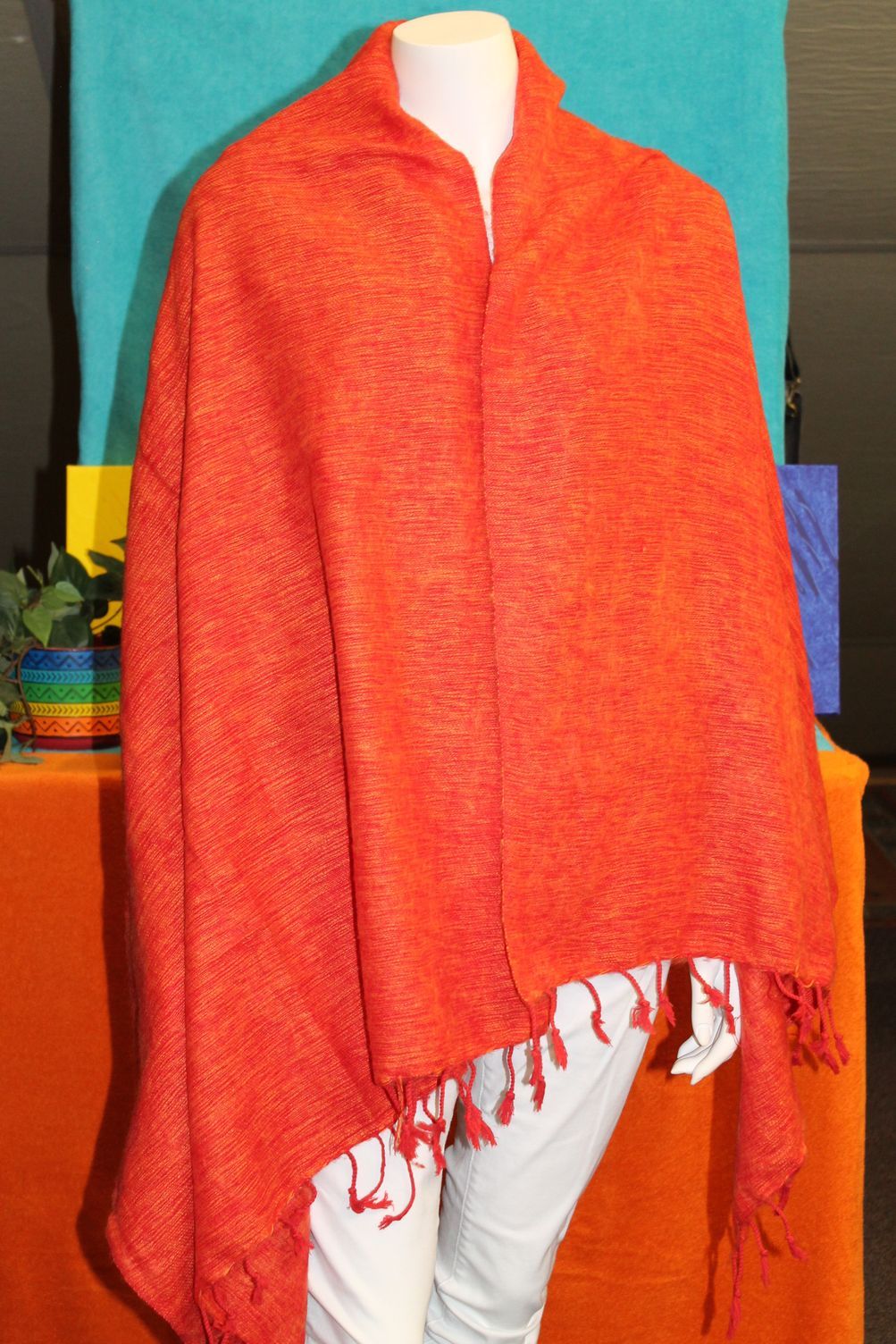 Een mannequin met een oranje sjaal en een witte broek