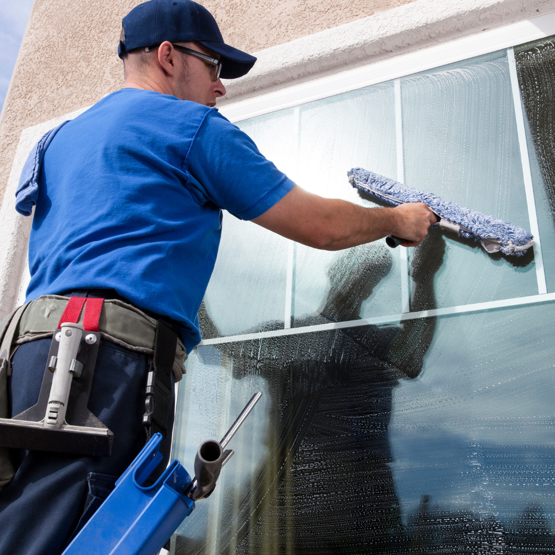 A man in a blue shirt is cleaning a window