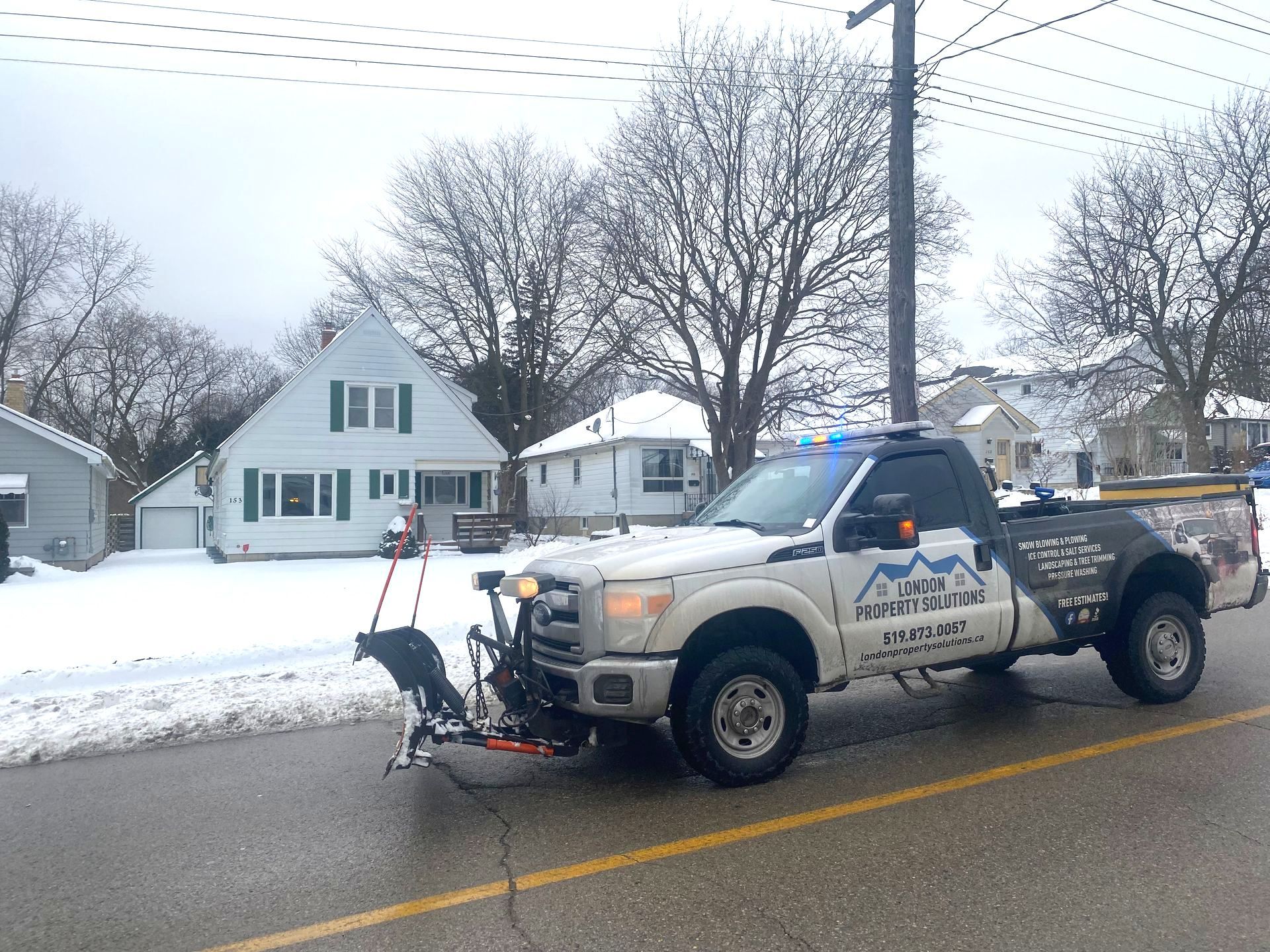 A snow plow is parked on the side of the road