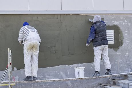 contractors applying stucco in the wall