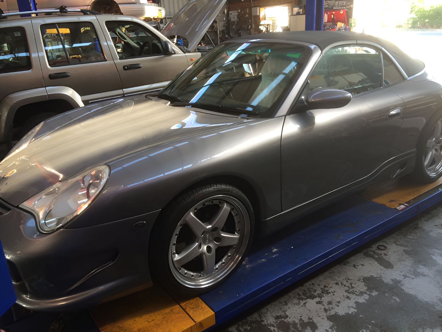 A Gray Sports Car is Parked on a Lift in a Garage — One Stop Service and Suspension Centre In Port Macquarie, NSW