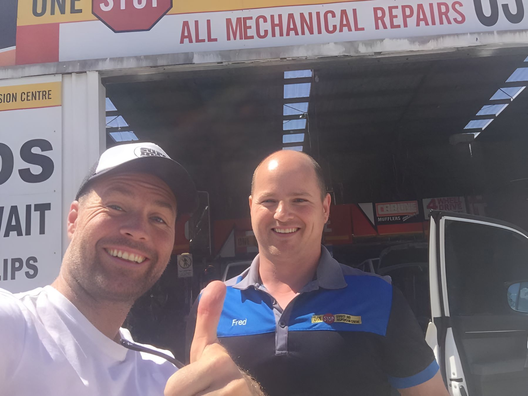 Two Men Are Shaking Hands in Front of a Sign — One Stop Service and Suspension Centre In Port Macquarie, NSW