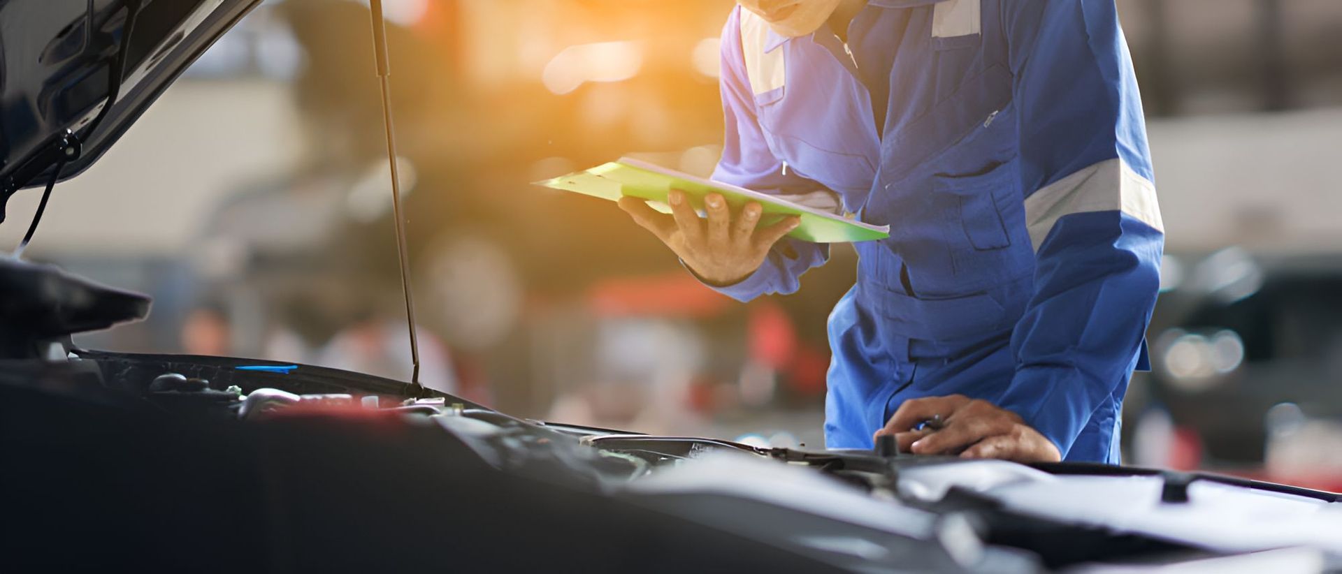 A Mechanic is Looking at a Clipboard While Working on a Car — One Stop Service and Suspension Centre In Port Macquarie, NSW