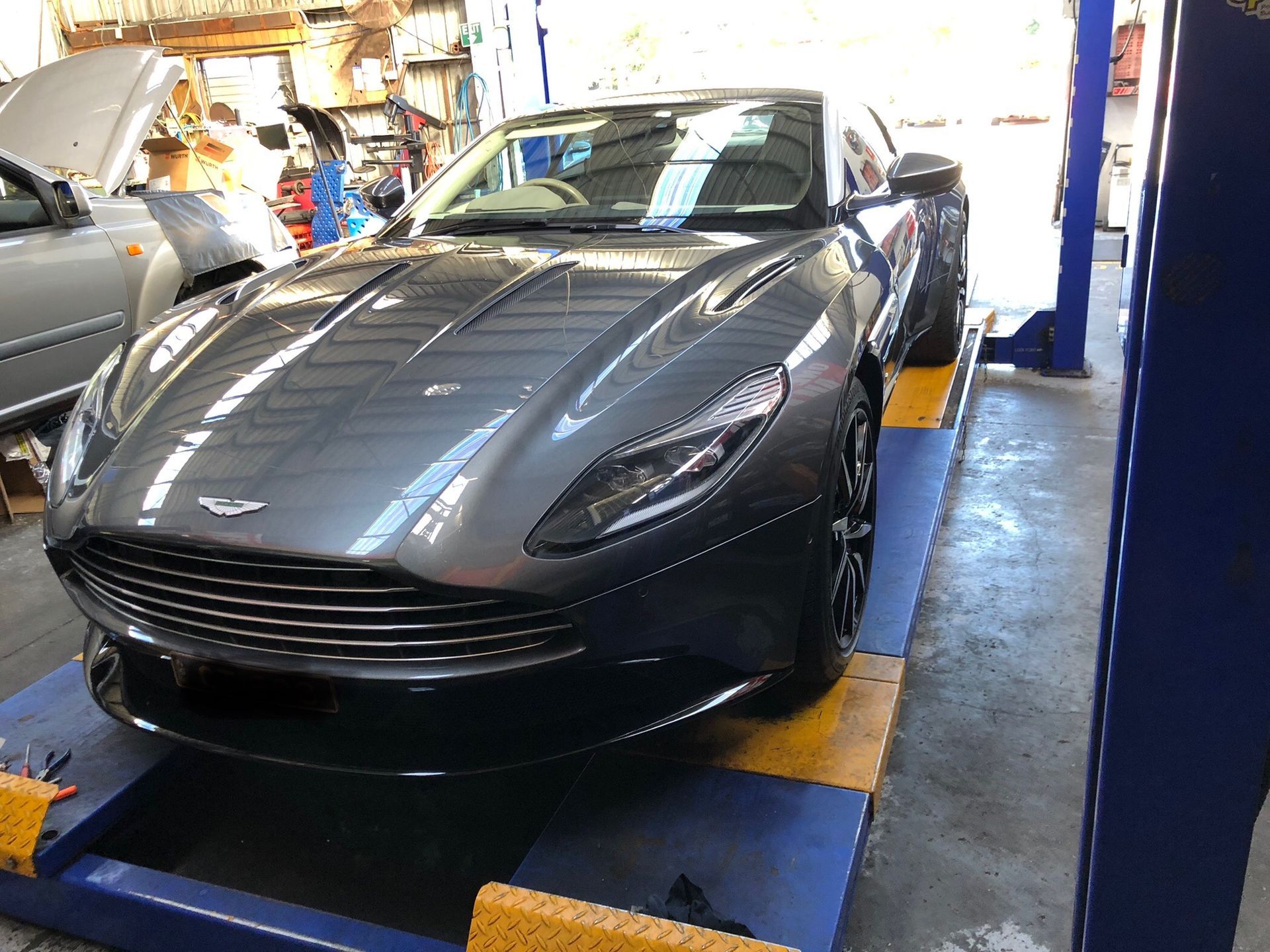 A Gray Sports Car is Parked on a Lift in a Garage — One Stop Service and Suspension Centre In Port Macquarie, NSW