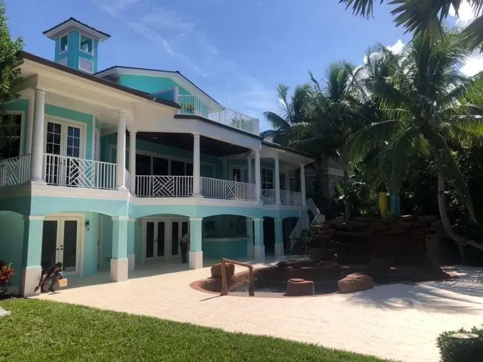 A large house with a lot of windows is surrounded by palm trees.