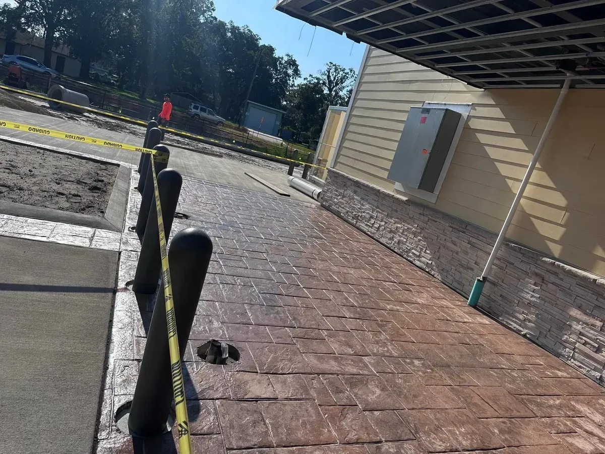 A brick walkway with a fence and a building in the background