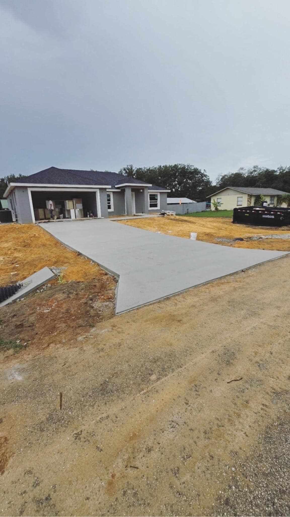 A concrete driveway leading to a house under construction.