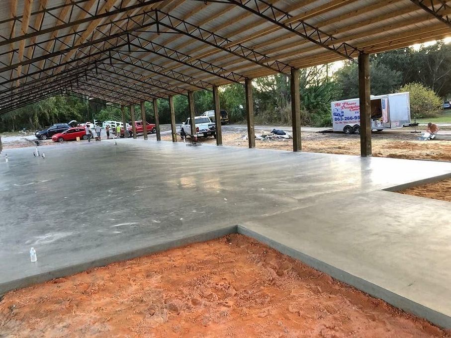 A concrete floor under a metal roof with a truck parked in the background.