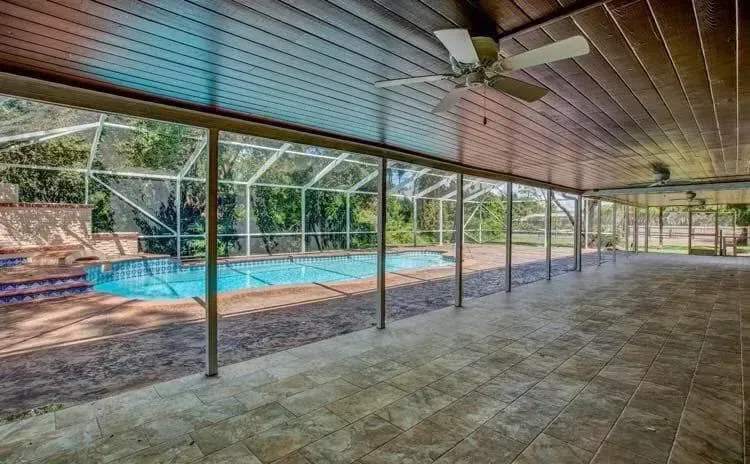 A large covered patio with a swimming pool in the background.