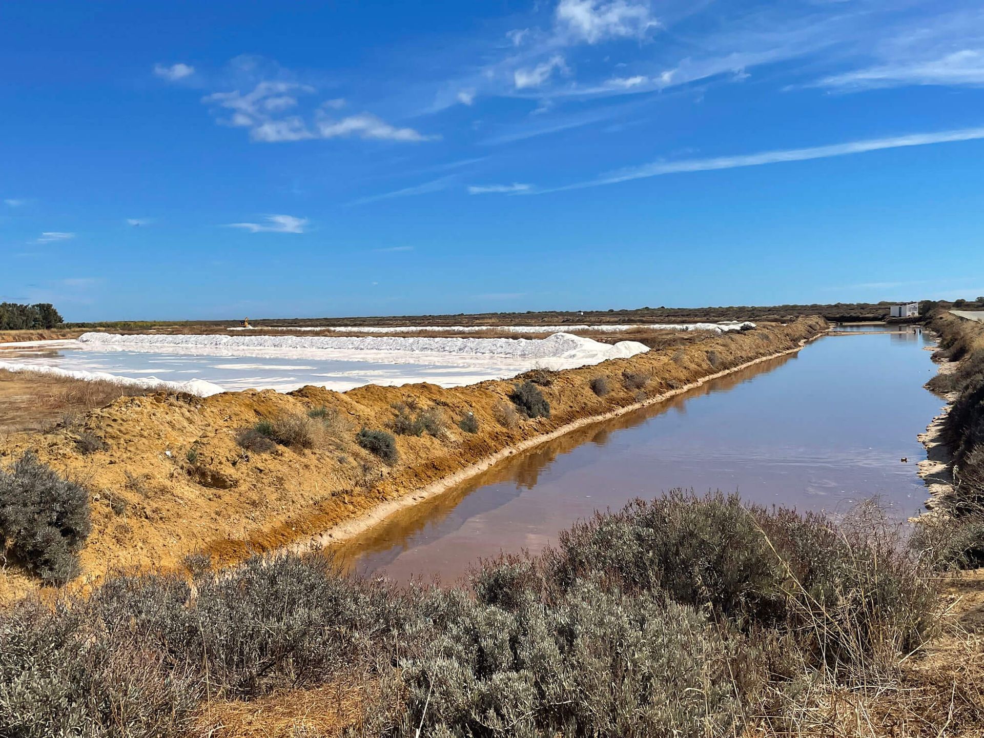Algarve, Salzwiesen: Ein Fluss fließt durch eine Landschaft mit einem blauen Himmel im Hintergrund.