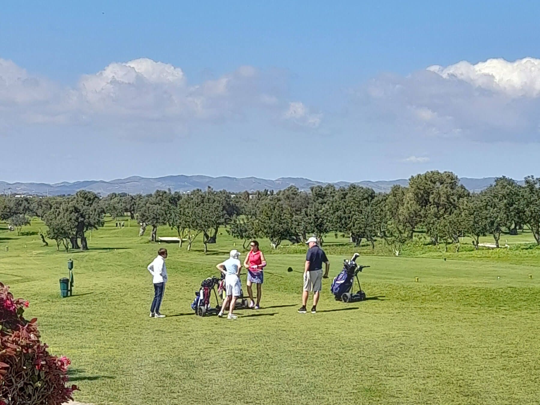 Algarve: Eine Gruppe von Menschen steht auf einem üppig grünen Golfplatz.