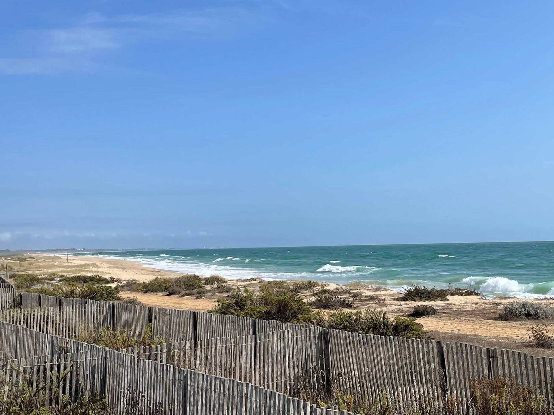 Ein Holzzaun umgibt einen Strand mit Blick auf das Meer an der Algarve.