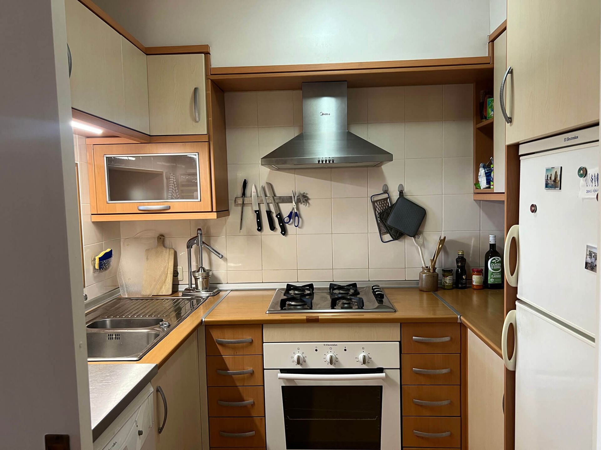 Eine Küche mit Holzschränken und einem weißen Kühlschrank, Apartment Cabanas