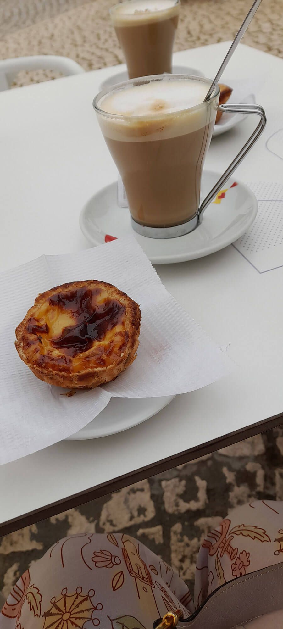 Zwei Tassen portugiesischer Kaffee und ein Gebäck auf einem Tisch.