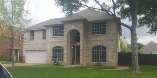 A large brick house with arched windows is sitting on top of a lush green lawn.