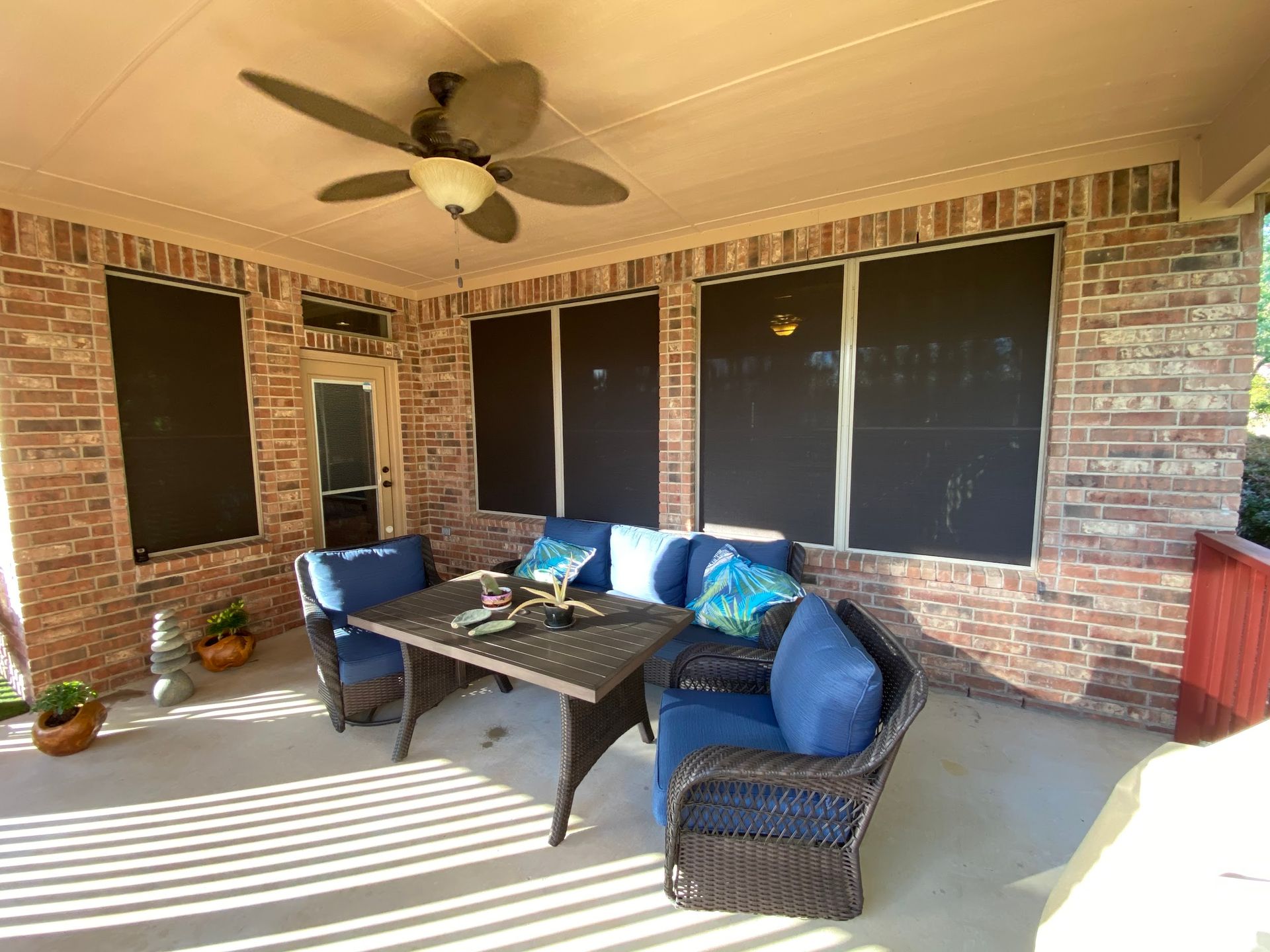 A porch with a couch , chairs , table and ceiling fan.